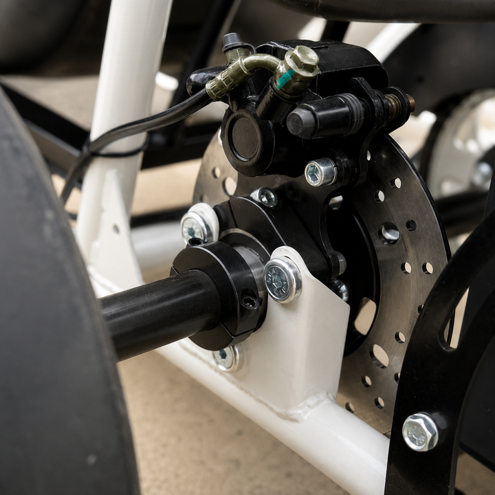 Close-up of a motorcycle or bicycle wheel hub assembly with a black brake caliper, silver brake disc, white frame tube, and black wheel rim.