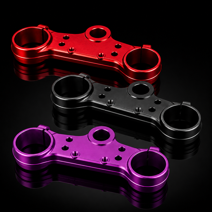 Three metal linkage components in red, black, and purple on a reflective black surface.
