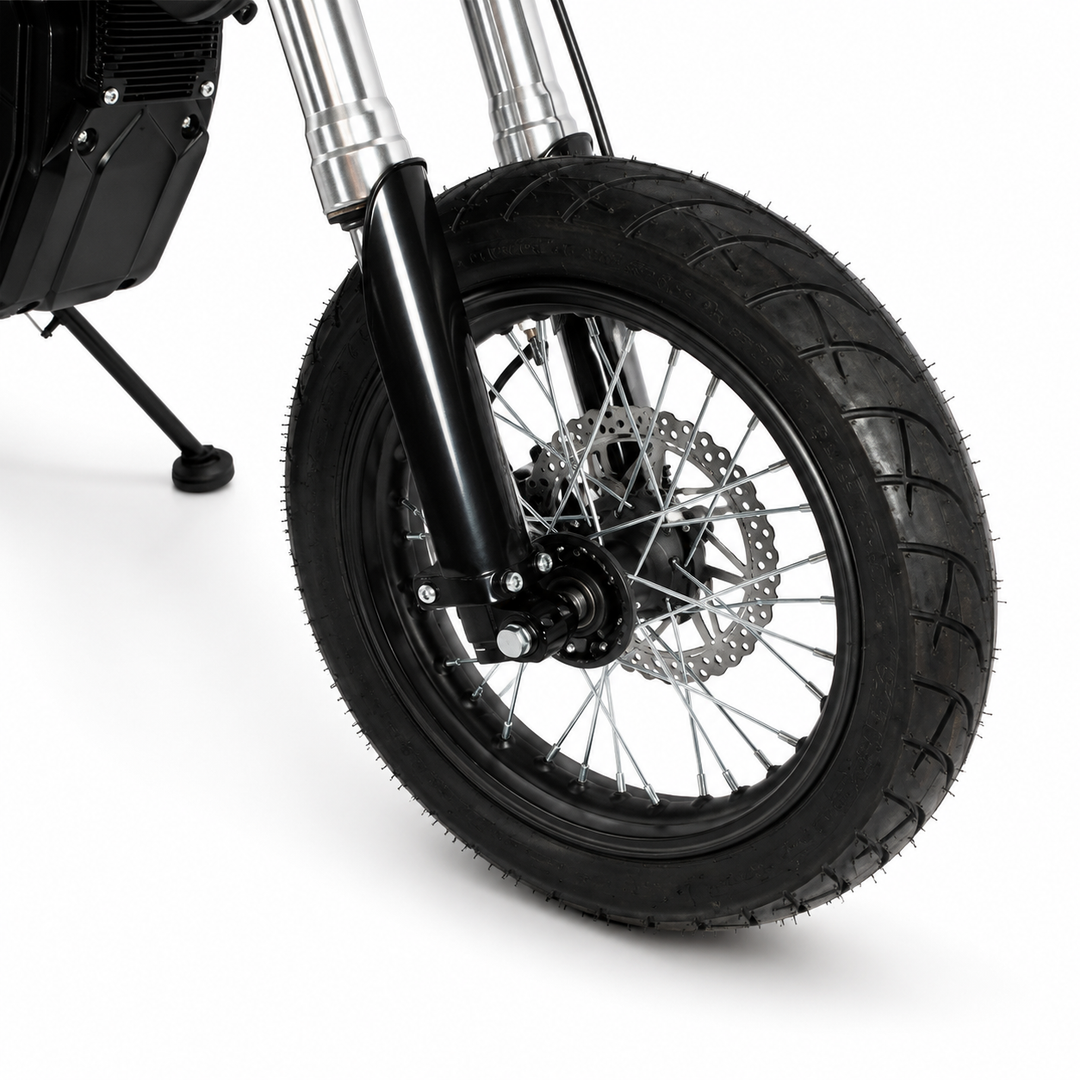 Close-up of a motorcycle front wheel with a black knobby tire, silver spoked rim, disc brake, and black front fork on a white studio background.
