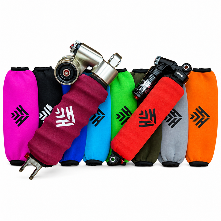 Six colorful motorcycle handlebar grips in pink, black, blue, green, red, gray, and orange, each with a black logo, displayed with a silver metal clamp on a white background.