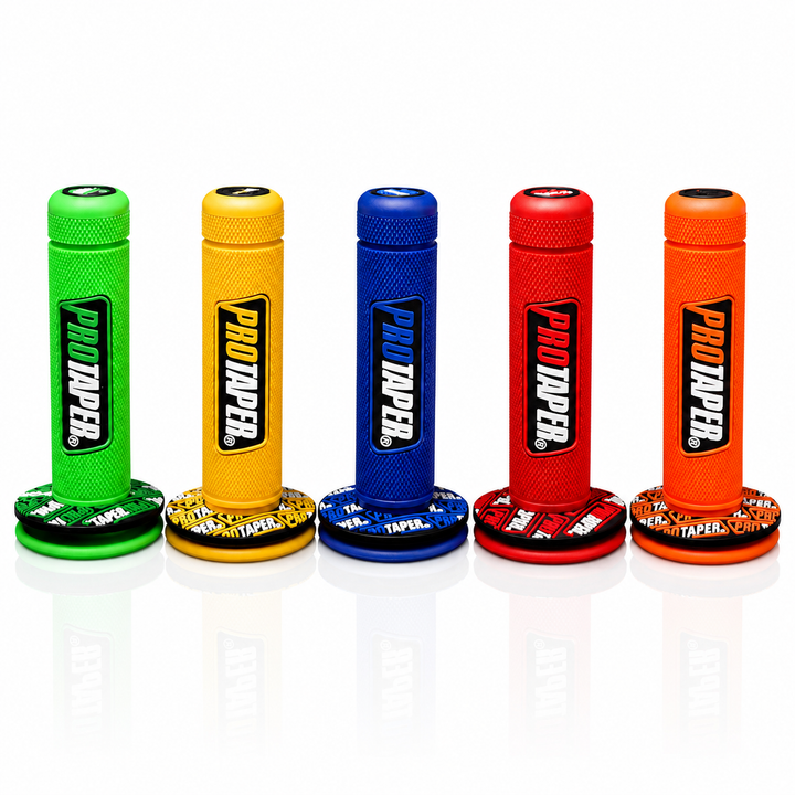 Five PRO TAPER bicycle handlebar tape spools in green, yellow, blue, red, and orange, lined up side-by-side on a reflective white surface.
