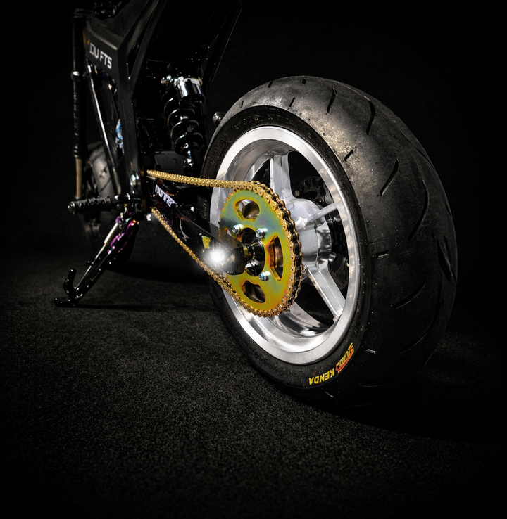 Close-up of a motorcycle tire and chain on a dark background