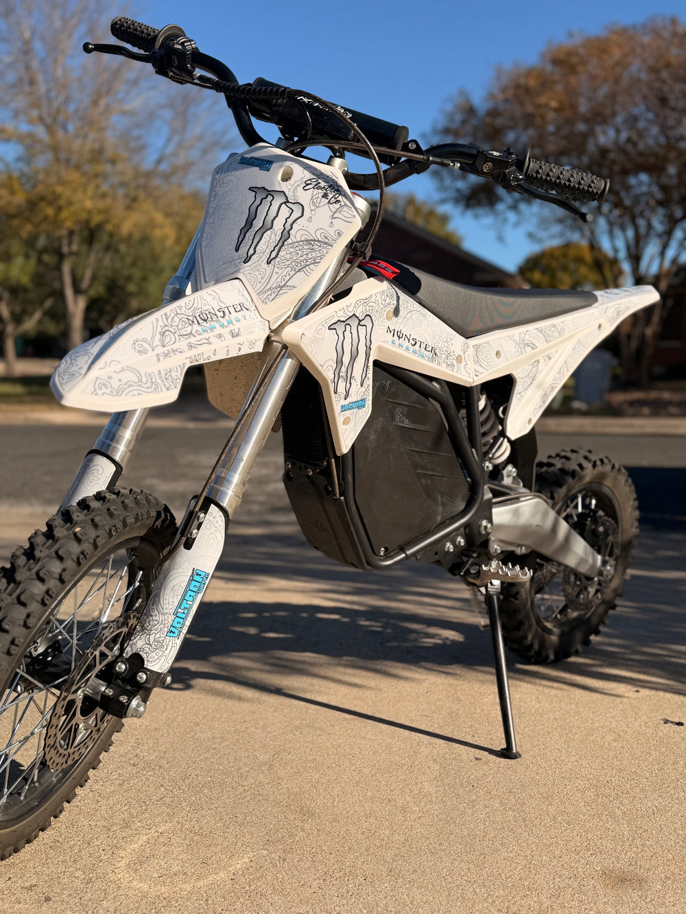 Motorcycle with Monster Energy branding on a paved road with trees in the background