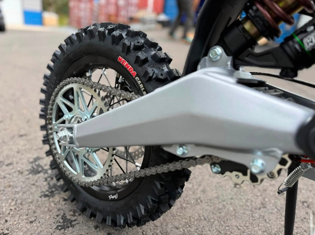 Close-up of a motorcycle wheel and chain on a road